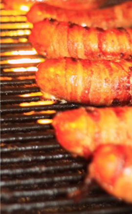 sausages wrapped in bacon on BBQ